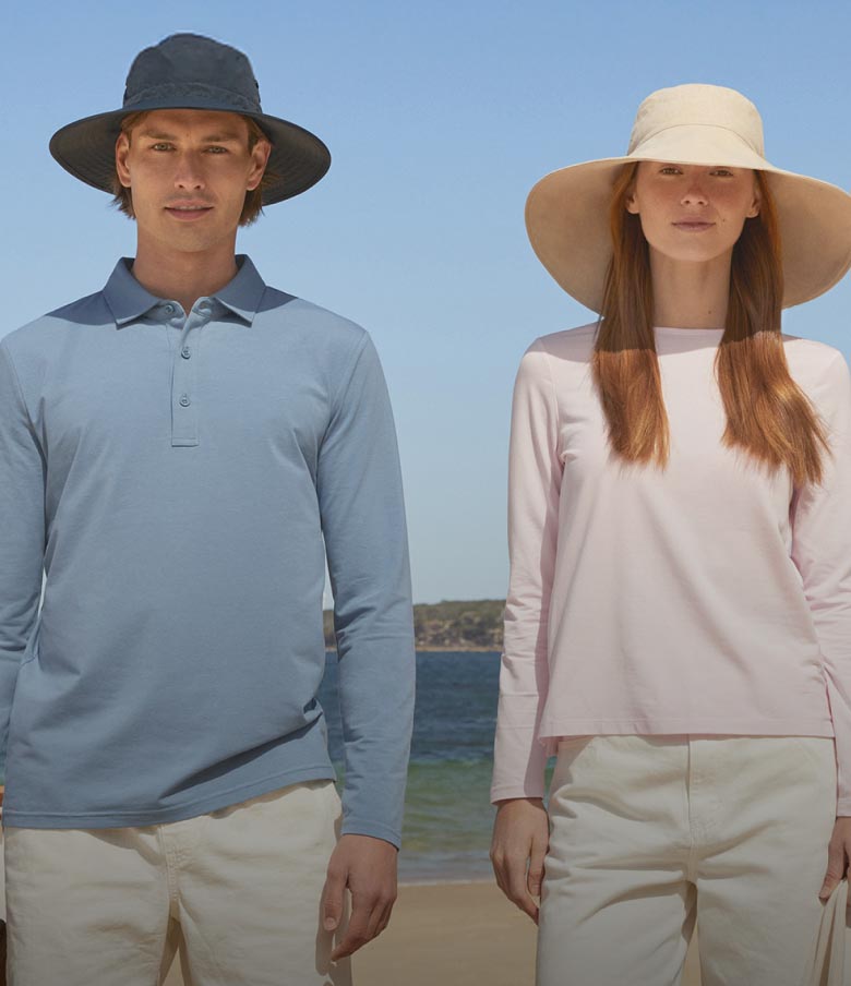 Two people wearing sun hats on a beach with ocean view