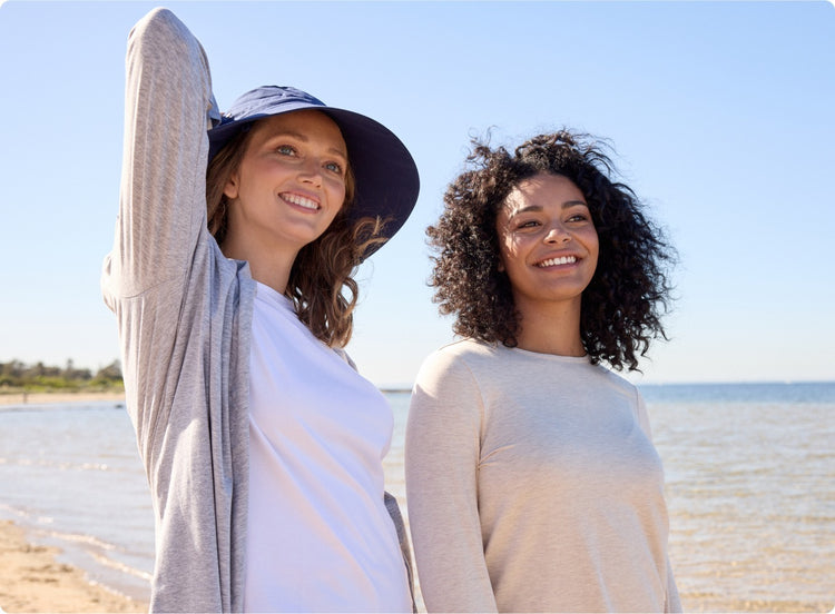Two women standing on a beach with clear blue sky